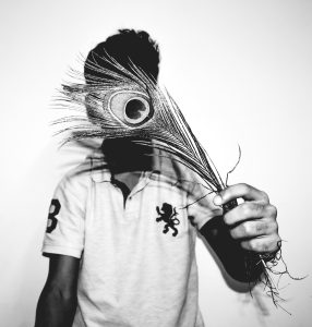Man hiding behind peacock feather to show we are up front and honest